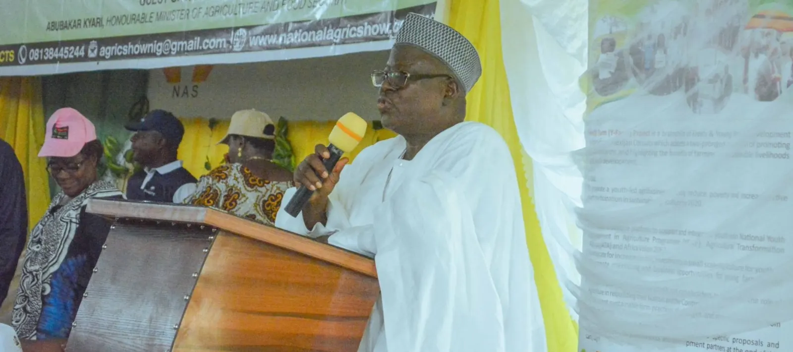 An official addressing attendees from the podium at a National Agricultural Show ceremony